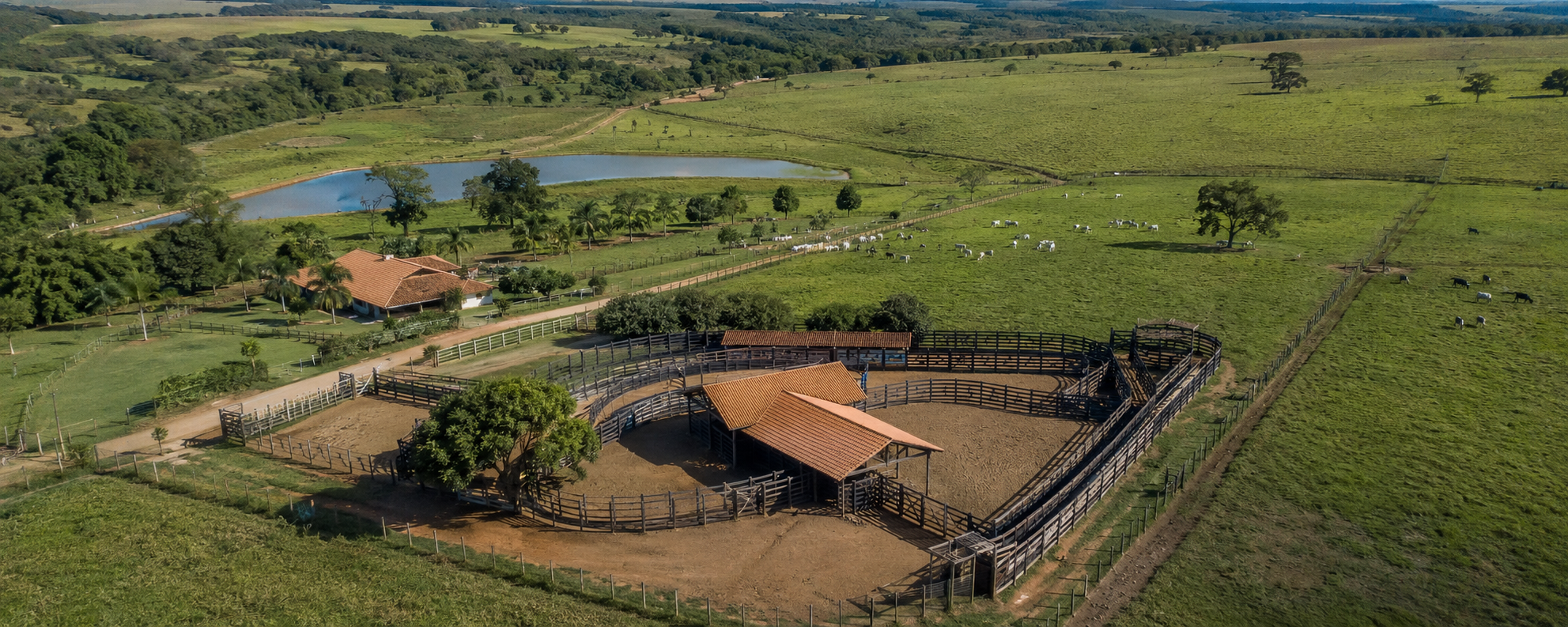 Vista aérea panorâmica de fazenda com curral circular, sede, açude e pastagens